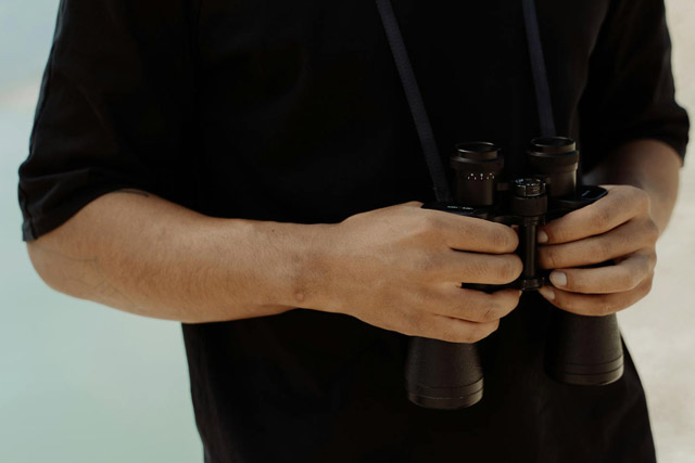 Man holding binoculars in order to prepare for whale watching.