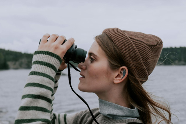 Young woman using binoculars and engaging in responsible whale watching.