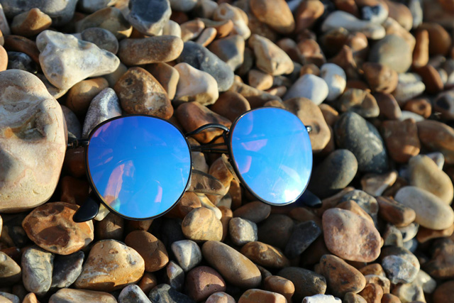 Polarized sunglasses laying on the rocks of a beach.