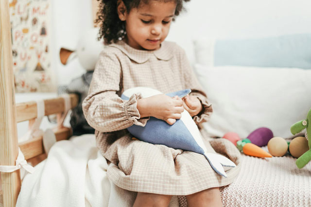 Young girl playing with a toy whale.