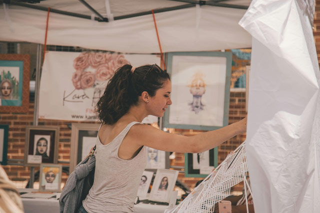 Woman shopping for a souvenir at an outdoor art shop.