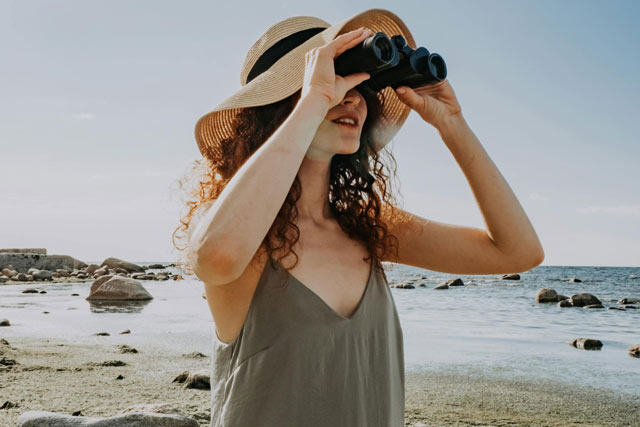 Young woman whale watching with binoculars.